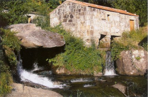 Imagen exterior de un molino en Caldas de Reis con el río al lado.. 